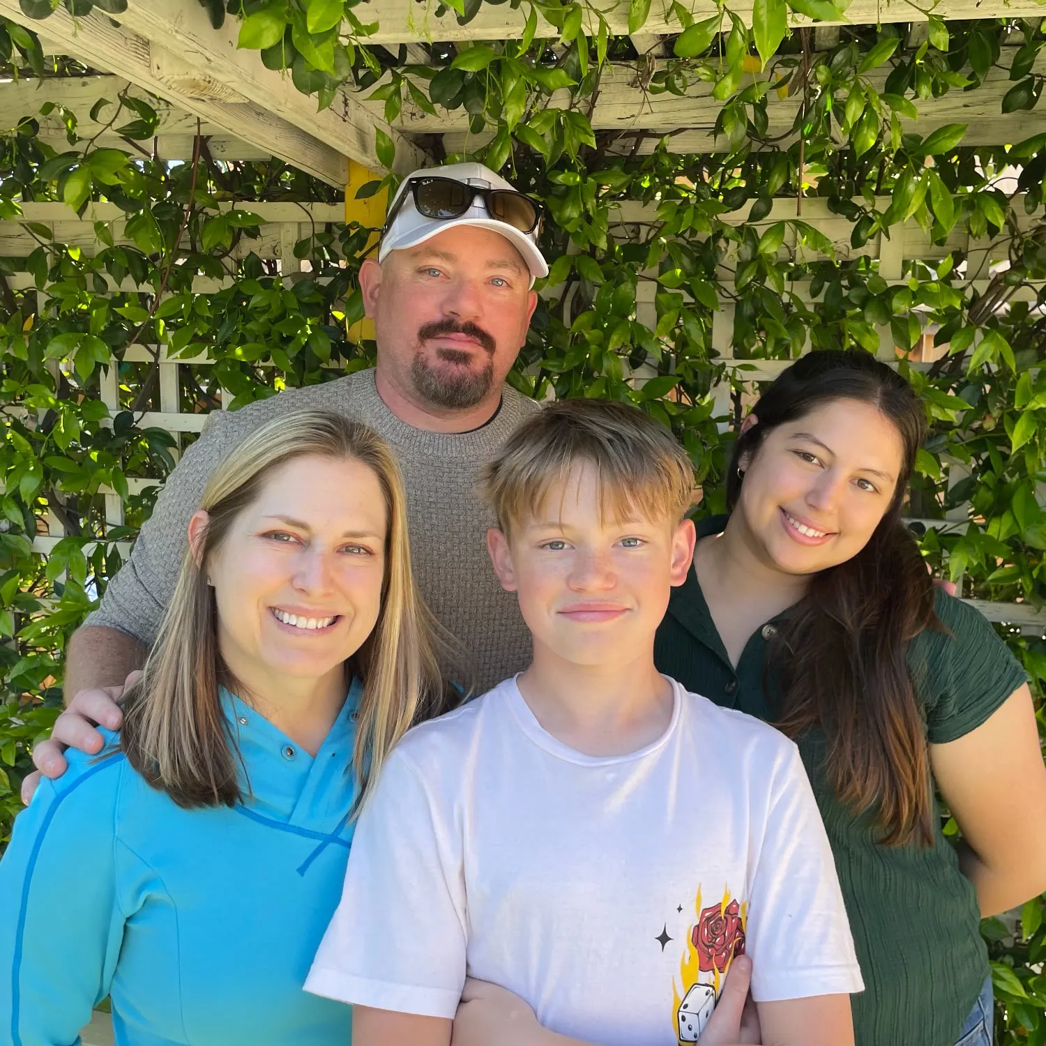 Carl Parker with his wife and their two children, outdoors under a garden trellis