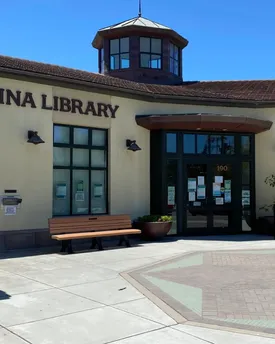 The entrance to Marina Library on a clear day, a bench outside and an octagonal glass cupola above the tiled roof.